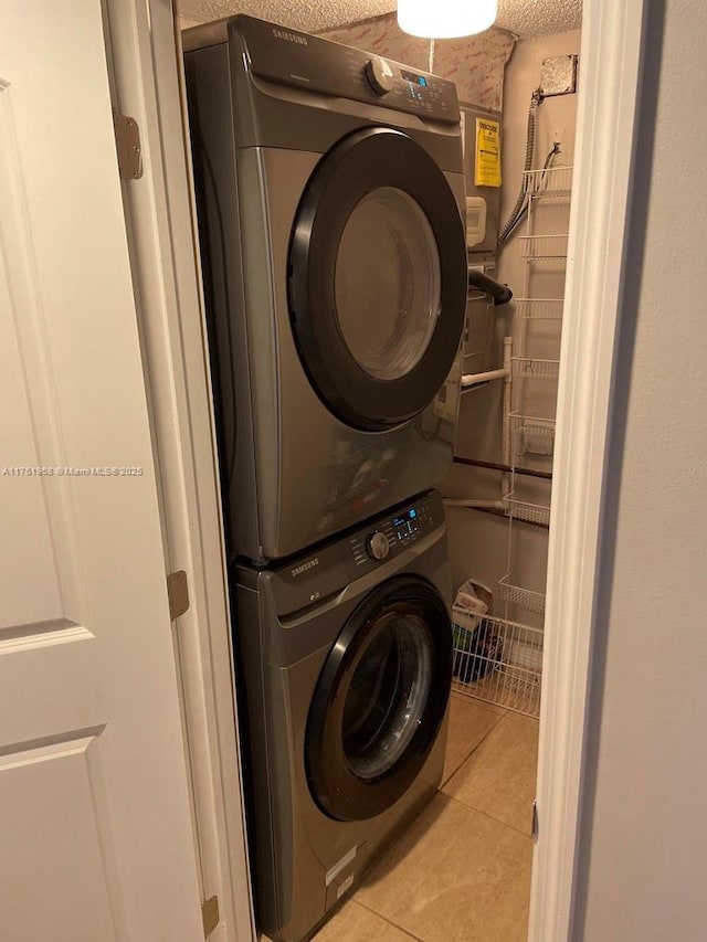 washroom featuring light tile patterned floors, stacked washer and dryer, and laundry area