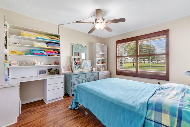 bedroom with ceiling fan, built in desk, and wood finished floors