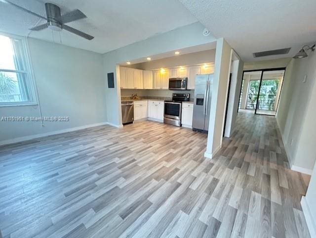 kitchen with baseboards, white cabinets, visible vents, open floor plan, and stainless steel appliances