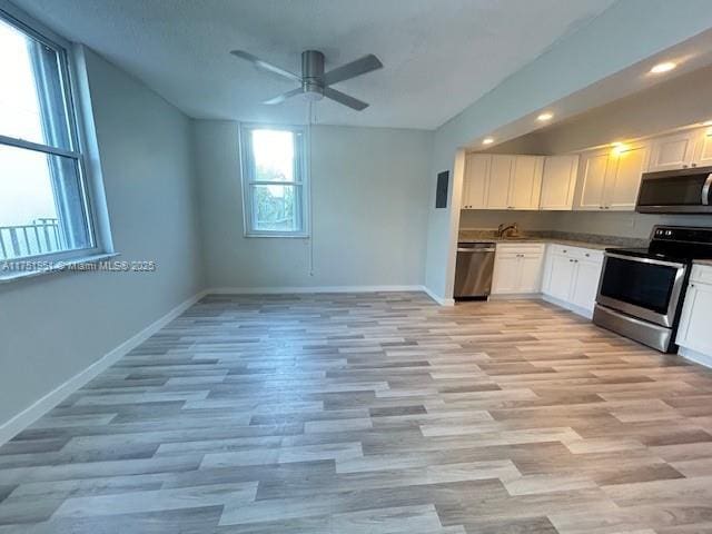 kitchen featuring baseboards, a ceiling fan, appliances with stainless steel finishes, light wood-type flooring, and white cabinetry