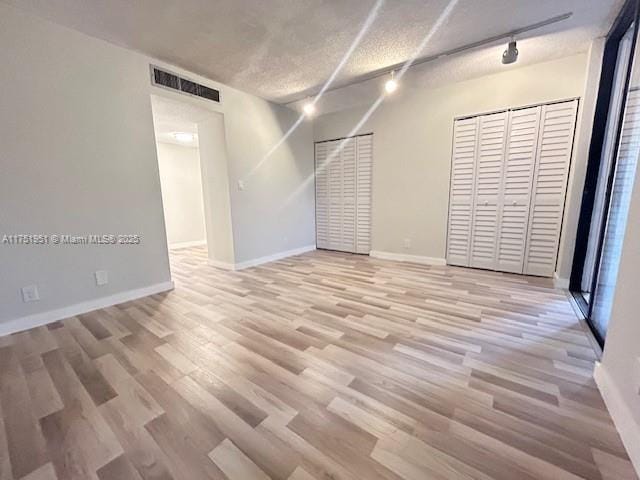 unfurnished room featuring light wood-style floors, baseboards, visible vents, and track lighting