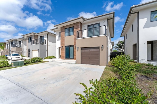 view of front facade with driveway, a garage, a balcony, a residential view, and stucco siding