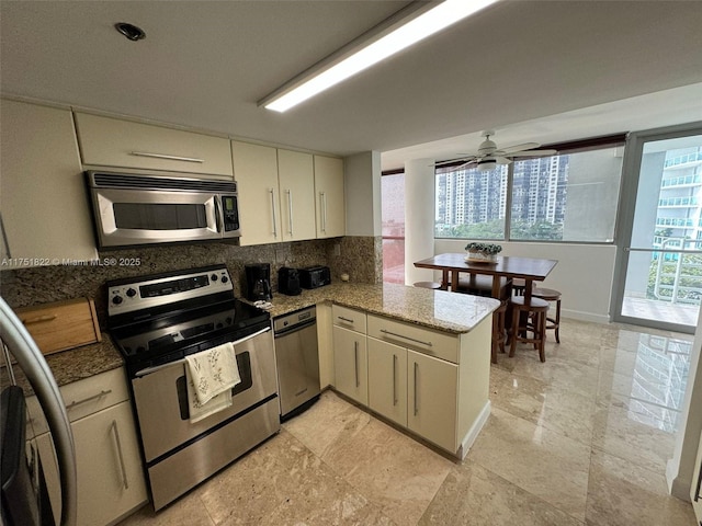2025 Brickell Ave Unit 901, Miami, FL 33129 - kitchen featuring appliances with stainless steel finishes, a peninsula, decorative backsplash, a ceiling fan, and light stone countertops