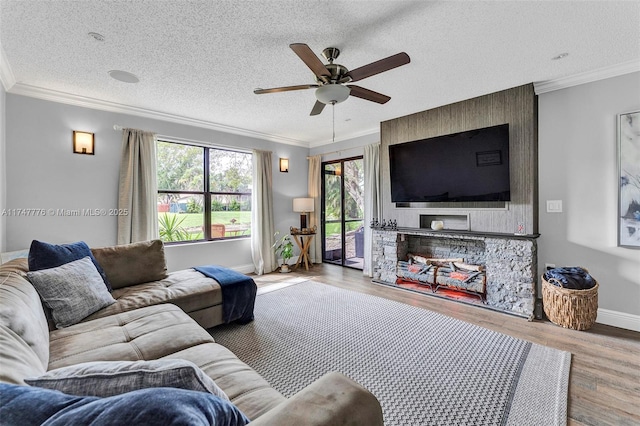 living room featuring baseboards, a textured ceiling, ornamental molding, and wood finished floors