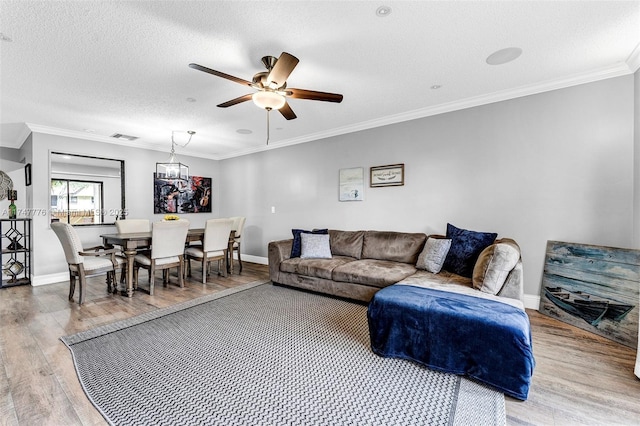 living area with ornamental molding, visible vents, a textured ceiling, and wood finished floors