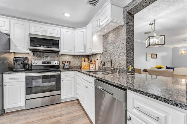 kitchen featuring a sink, white cabinets, ornamental molding, appliances with stainless steel finishes, and light wood finished floors