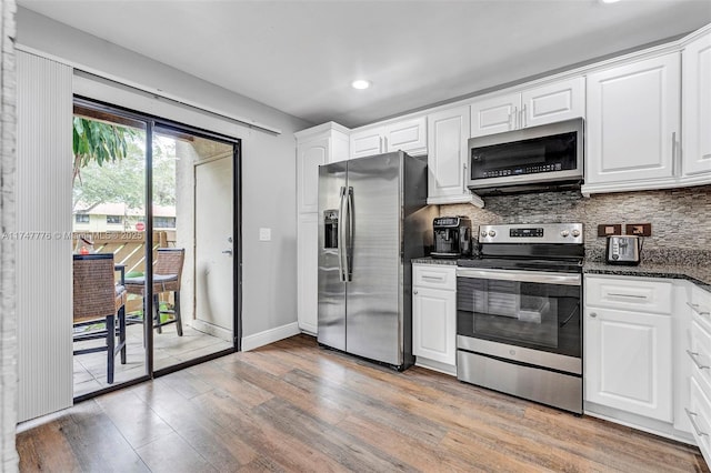 kitchen with tasteful backsplash, light wood-style flooring, appliances with stainless steel finishes, white cabinets, and baseboards