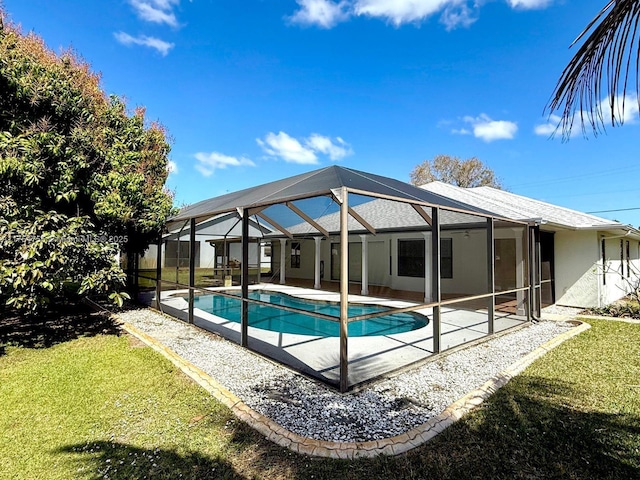 pool featuring glass enclosure, a patio, and a lawn