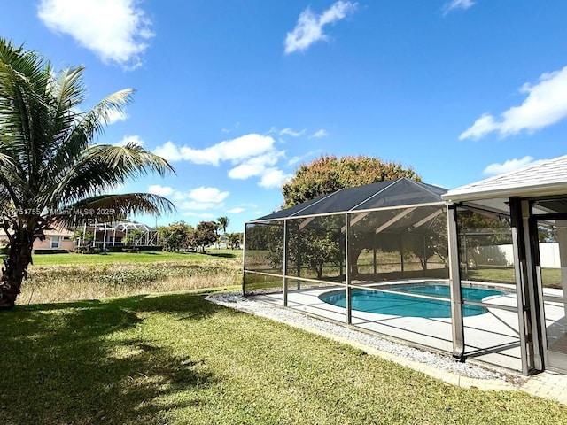 outdoor pool with glass enclosure, a lawn, and a patio