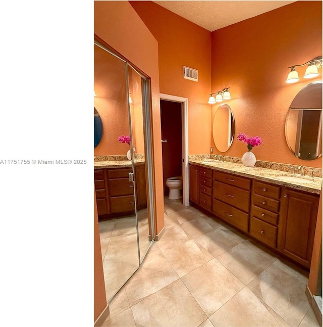 full bathroom featuring double vanity, visible vents, toilet, and a sink