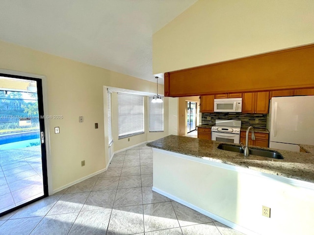 kitchen featuring light tile patterned flooring, white appliances, a sink, brown cabinets, and tasteful backsplash