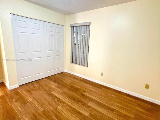 unfurnished bedroom featuring a closet, baseboards, and wood finished floors