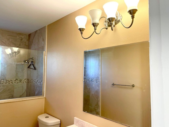 bathroom featuring a chandelier, tiled shower, and toilet