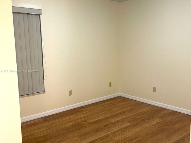 spare room with baseboards and wood finished floors