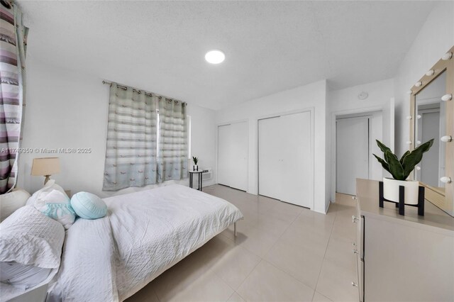 bedroom featuring light tile patterned floors and two closets