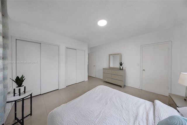 bedroom with tile patterned flooring and two closets