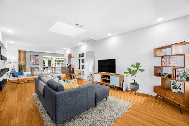 living area with light wood finished floors, a skylight, baseboards, visible vents, and recessed lighting