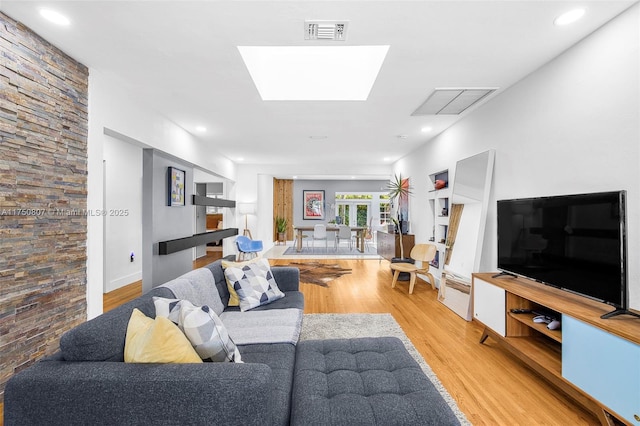 living room featuring a skylight, light wood-style flooring, visible vents, and recessed lighting