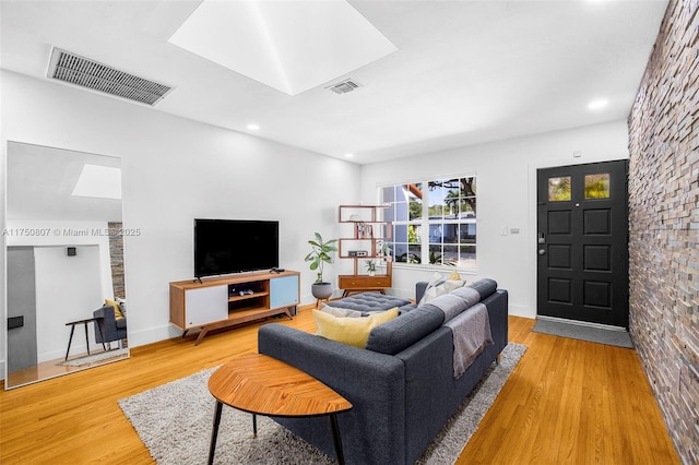 living room with a skylight, baseboards, visible vents, and wood finished floors