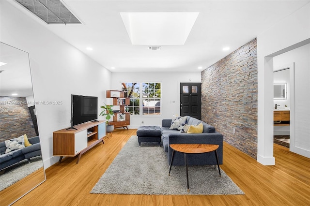 living room featuring light wood-style flooring, a skylight, and visible vents