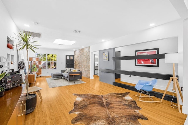 living area featuring a skylight, wood finished floors, visible vents, and recessed lighting