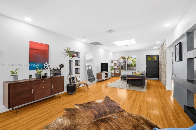 living room featuring light wood-type flooring, a skylight, visible vents, and recessed lighting