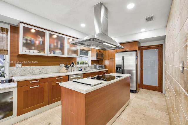 kitchen with stainless steel appliances, a kitchen island, visible vents, light stone countertops, and island exhaust hood