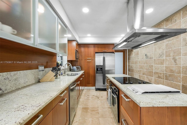 kitchen featuring island exhaust hood, stainless steel appliances, backsplash, brown cabinetry, and glass insert cabinets