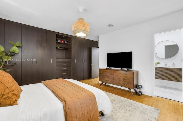 bedroom featuring ensuite bathroom and light wood-style flooring