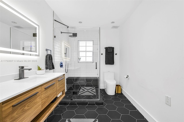 full bath with toilet, a stall shower, vanity, baseboards, and tile patterned floors