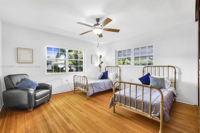 bedroom featuring multiple windows, ceiling fan, and wood finished floors