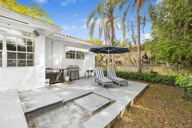 view of patio / terrace with a grill and fence