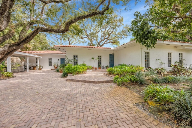 view of front of property with a tiled roof, a patio, and stucco siding