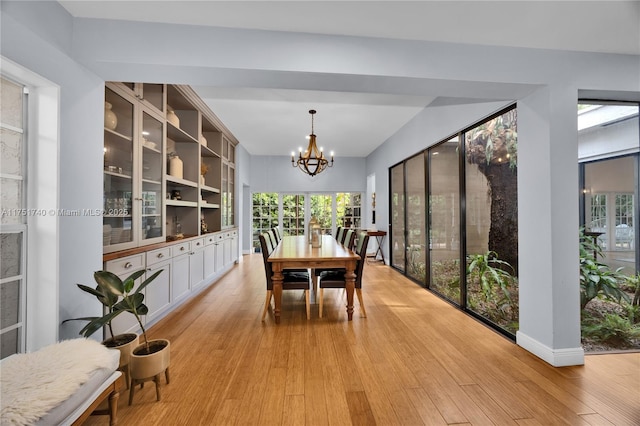 dining area with baseboards, a notable chandelier, and light wood finished floors