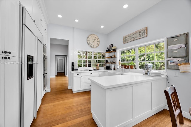 kitchen with light countertops, a sink, a peninsula, and white cabinetry