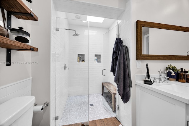 bathroom with toilet, a shower stall, and vanity