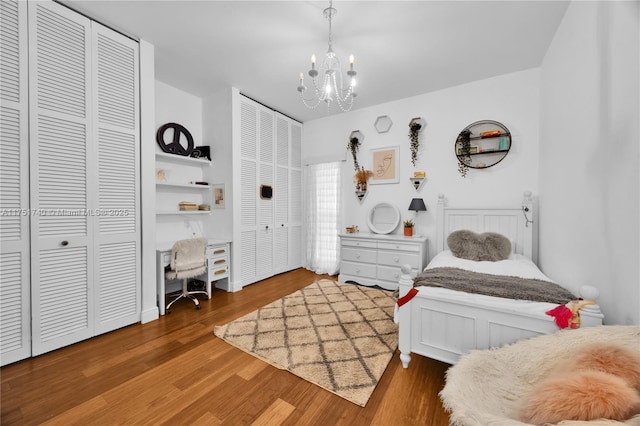 bedroom featuring multiple closets, a chandelier, and wood finished floors