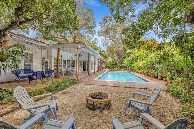 outdoor pool featuring a patio area, an outdoor living space with a fire pit, a ceiling fan, and french doors