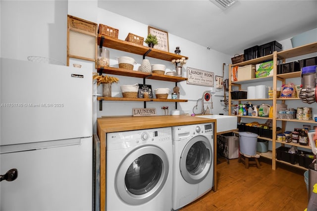 laundry room featuring laundry area, a sink, visible vents, light wood finished floors, and washer and clothes dryer