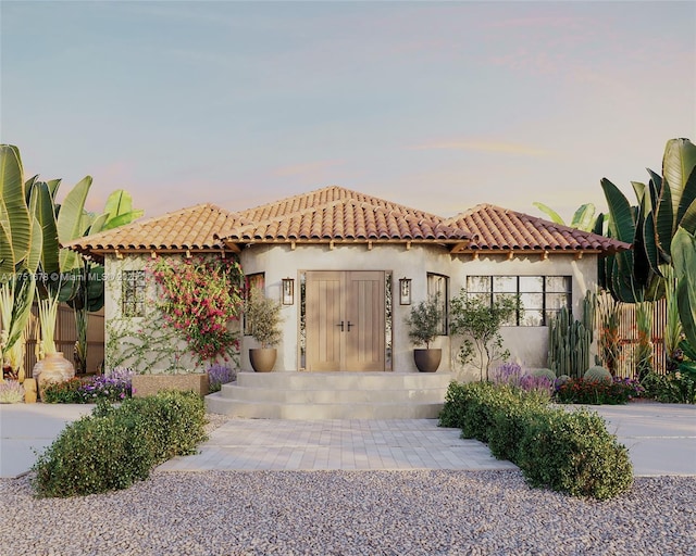 mediterranean / spanish home with a tile roof, fence, and stucco siding