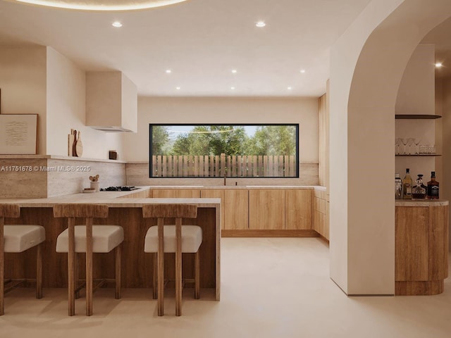 kitchen featuring a kitchen bar, modern cabinets, light brown cabinets, and backsplash