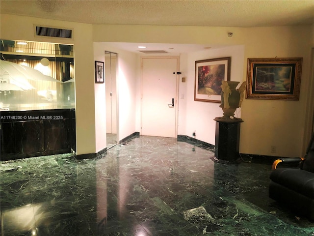 interior space with marble finish floor, baseboards, visible vents, and a textured ceiling