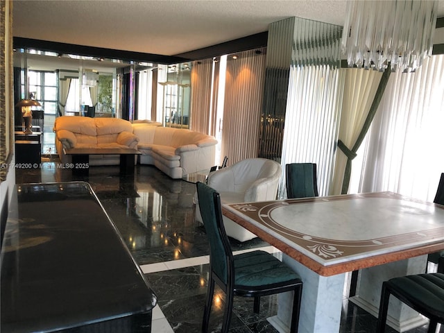dining area featuring marble finish floor, a textured ceiling, and a healthy amount of sunlight