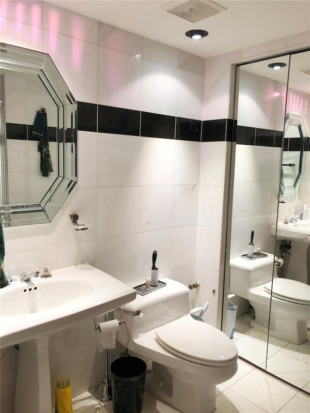 bathroom featuring toilet, tile patterned flooring, visible vents, and tile walls