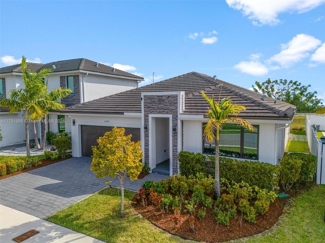 view of front of house with decorative driveway, a tiled roof, and an attached garage