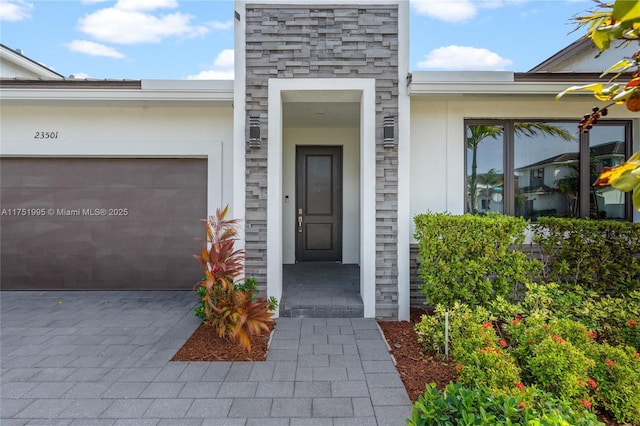 doorway to property with stone siding, decorative driveway, and stucco siding