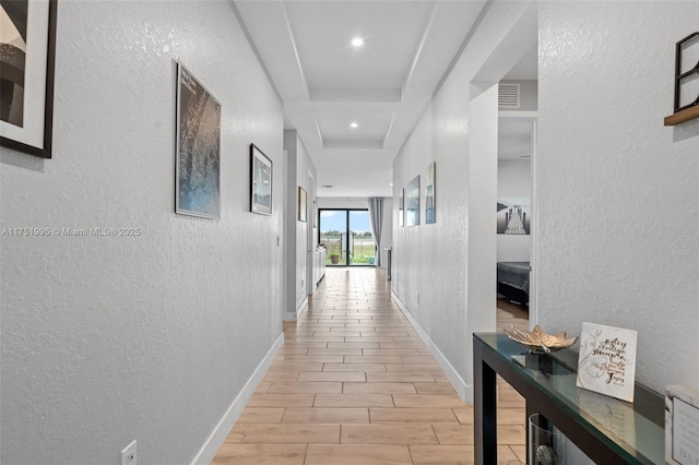 corridor with baseboards, visible vents, wood finish floors, and a textured wall