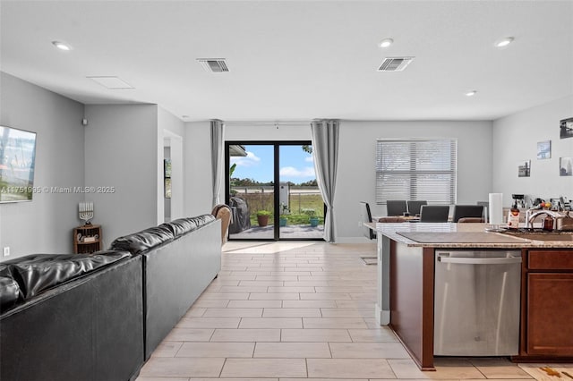 kitchen with a sink, visible vents, open floor plan, and dishwasher