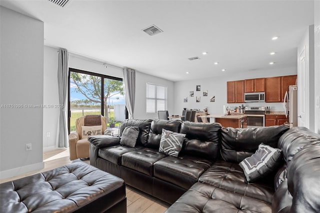 living area featuring light wood-style floors, recessed lighting, visible vents, and baseboards