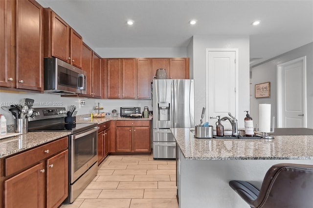 kitchen featuring light stone countertops, stainless steel appliances, a sink, and recessed lighting